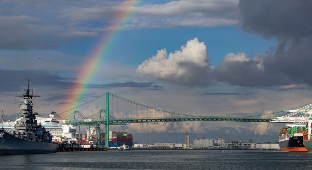 A rainbow over the Port of Los Angeles main channel, Battleship Iowa, a cruise ship, container port operations and Vincent Thomas suspension bridge. Credit Brad Nixon.